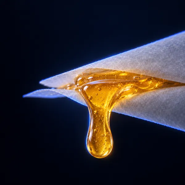 Goutte de live rosin ambré qui coule entre deux feuilles de papier cuisson