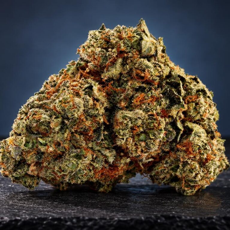 Beuh : fleur dense aux teintes vertes et orangées, couverte de cristaux brillants, sur fond bleu