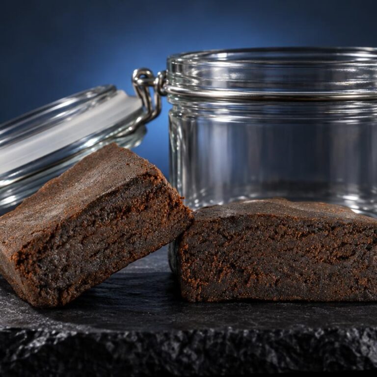 Conserver le hash : deux briques de hash brun foncé devant un pot hermétique en verre transparent, sur surface grise