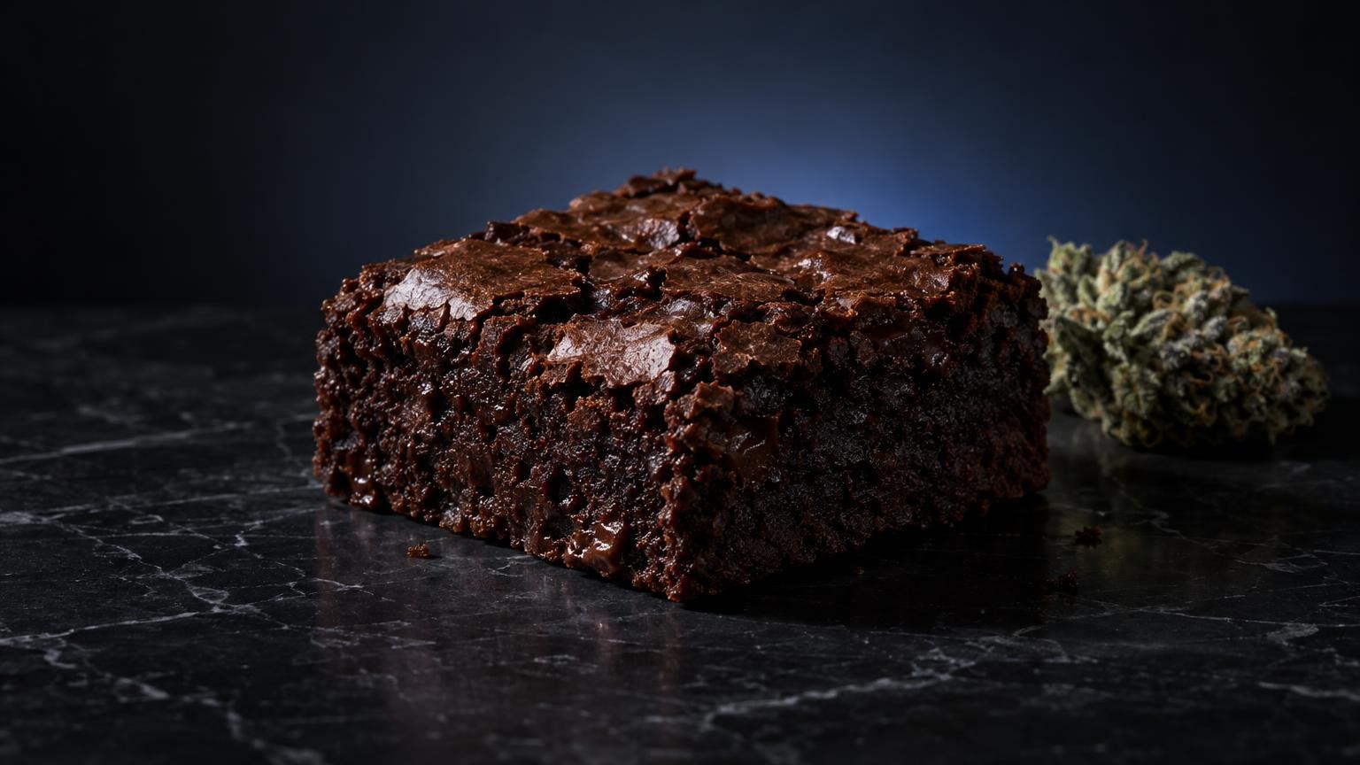 Chocoladebrownie met kruimels op donkere ondergrond naast cannabisblad, edibles kopen belgie