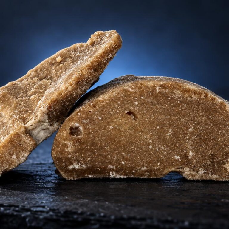 Deux morceaux de frozen hash de couleur dorée et beige, à texture granuleuse, posés sur surface noire