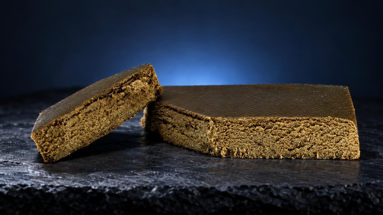 Two blocks of golden-brown Triple Zero with fine, crumbly texture on dark surface